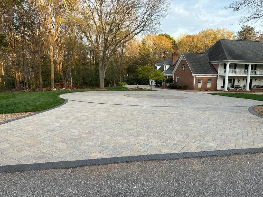 Large circular paver motor court in front of a white-columned brick colonial home