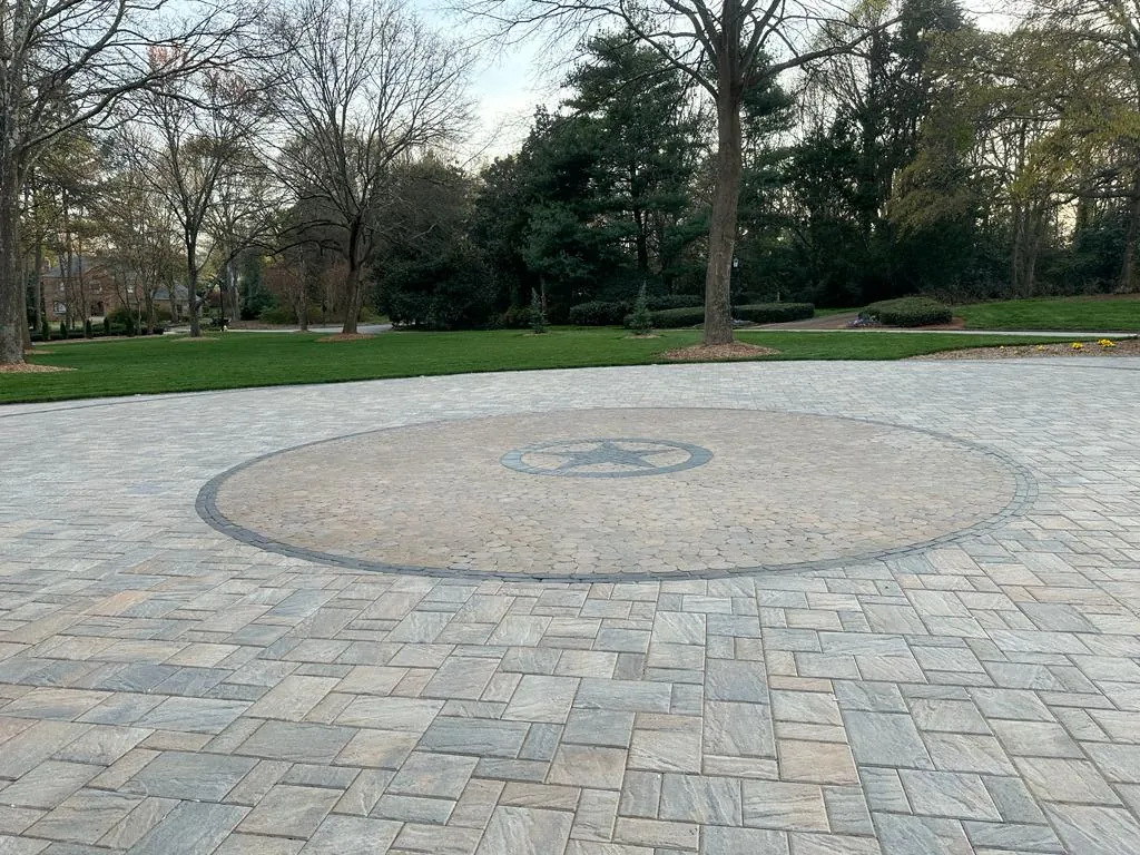 Paver courtyard with a matching star and compass medallion inlay, wooded surroundings