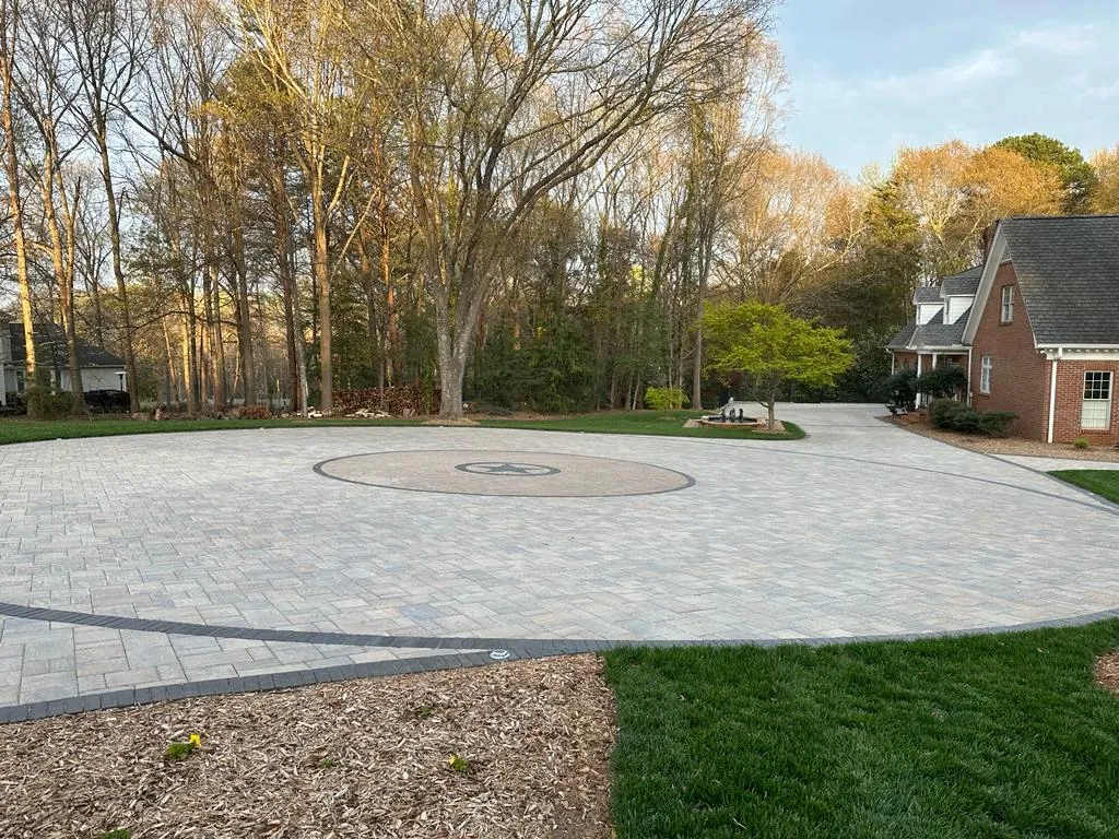 Circular paver courtyard with an inlaid star and compass medallion, red brick house, evening light