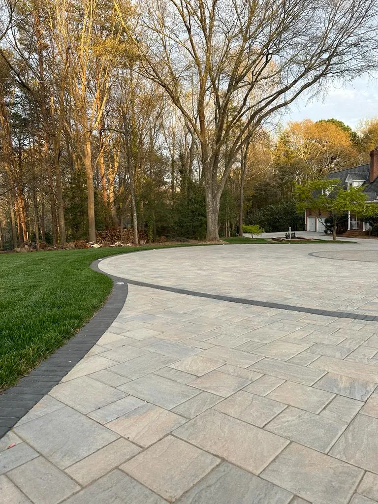 Curving paver driveway with a black banded border, winter, brick home in the distance