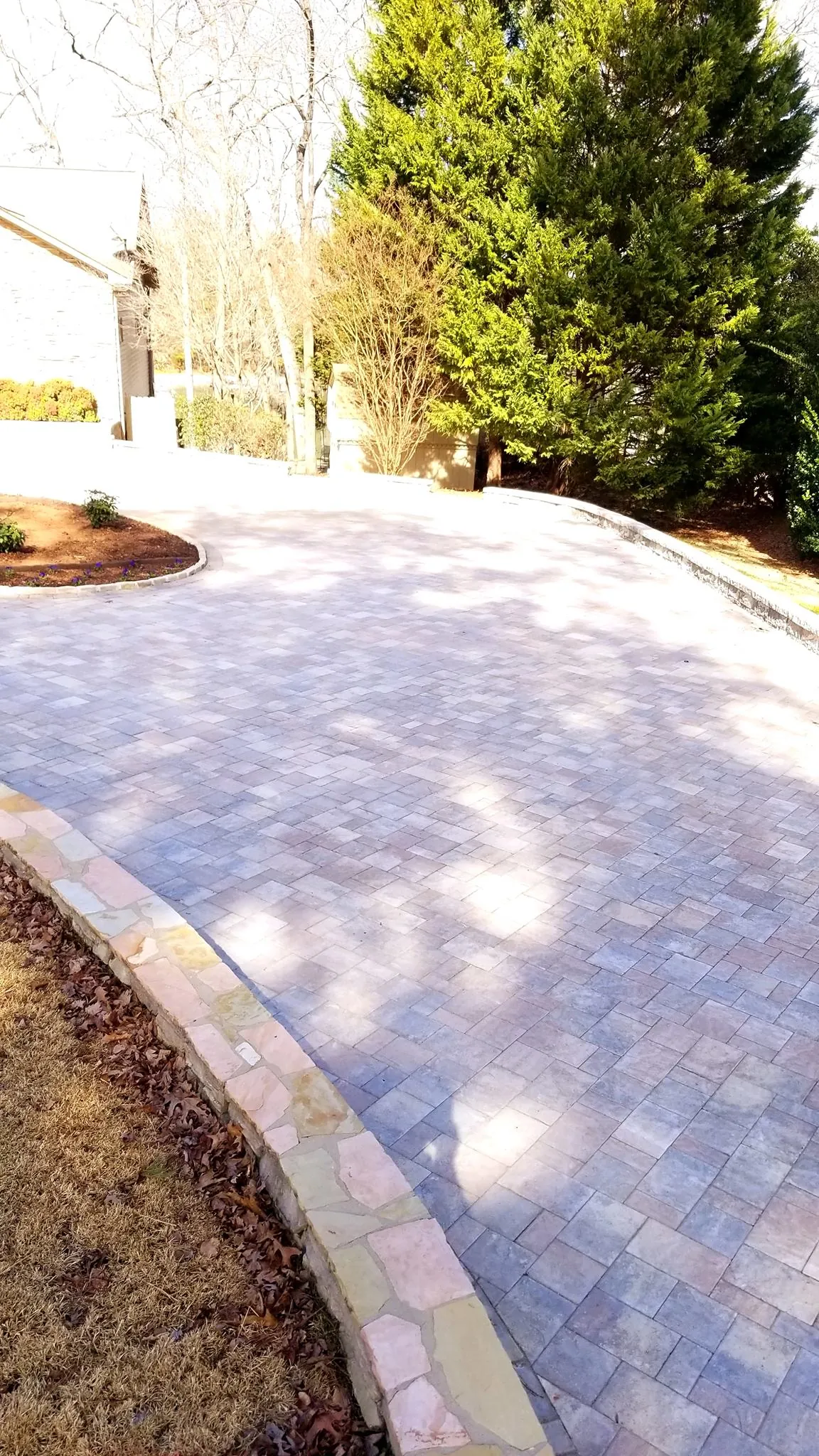 Curved paver driveway with a natural stone retaining wall, winter