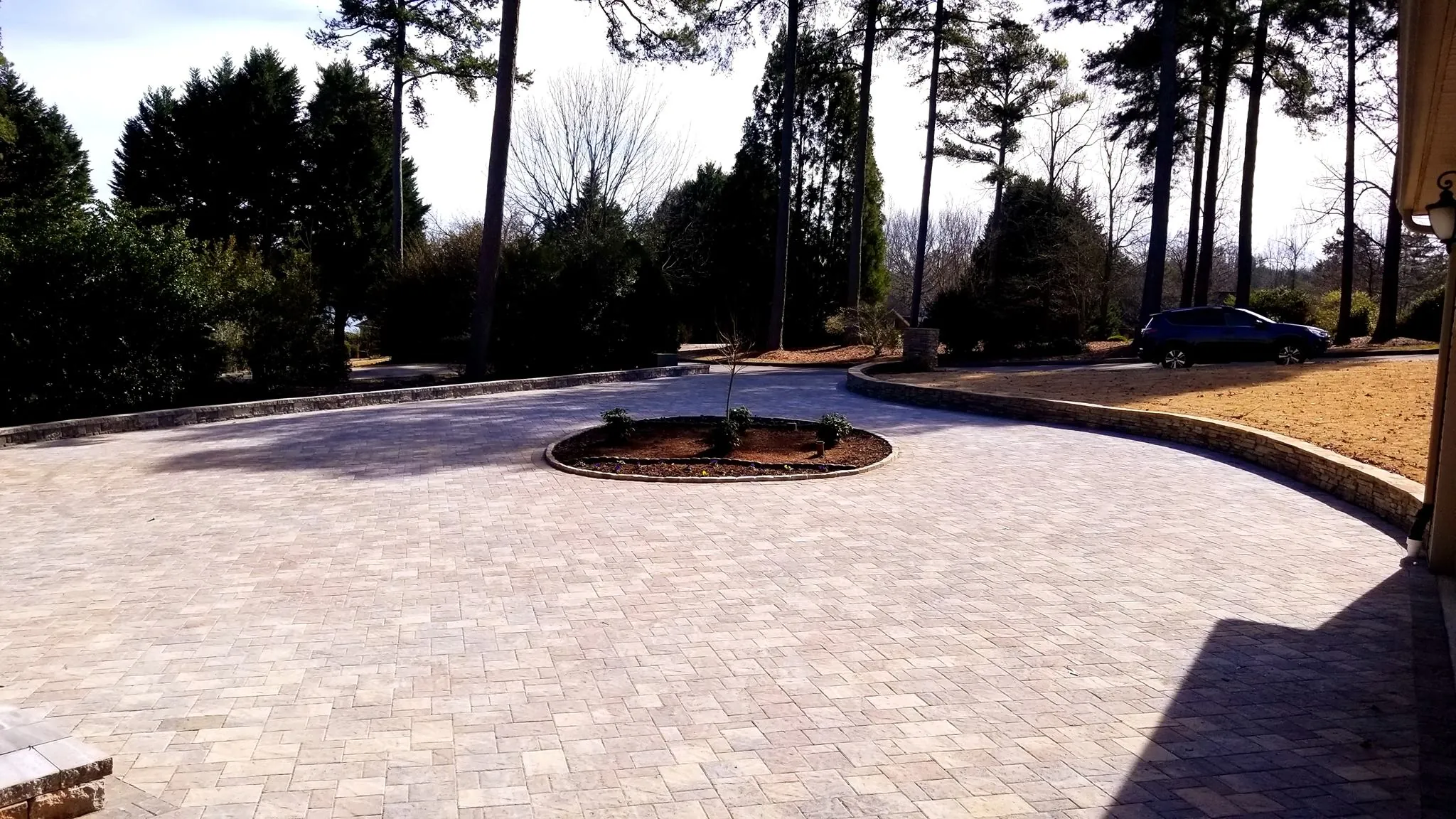 Circular paver driveway with a landscaped island and stone retaining wall, evening light