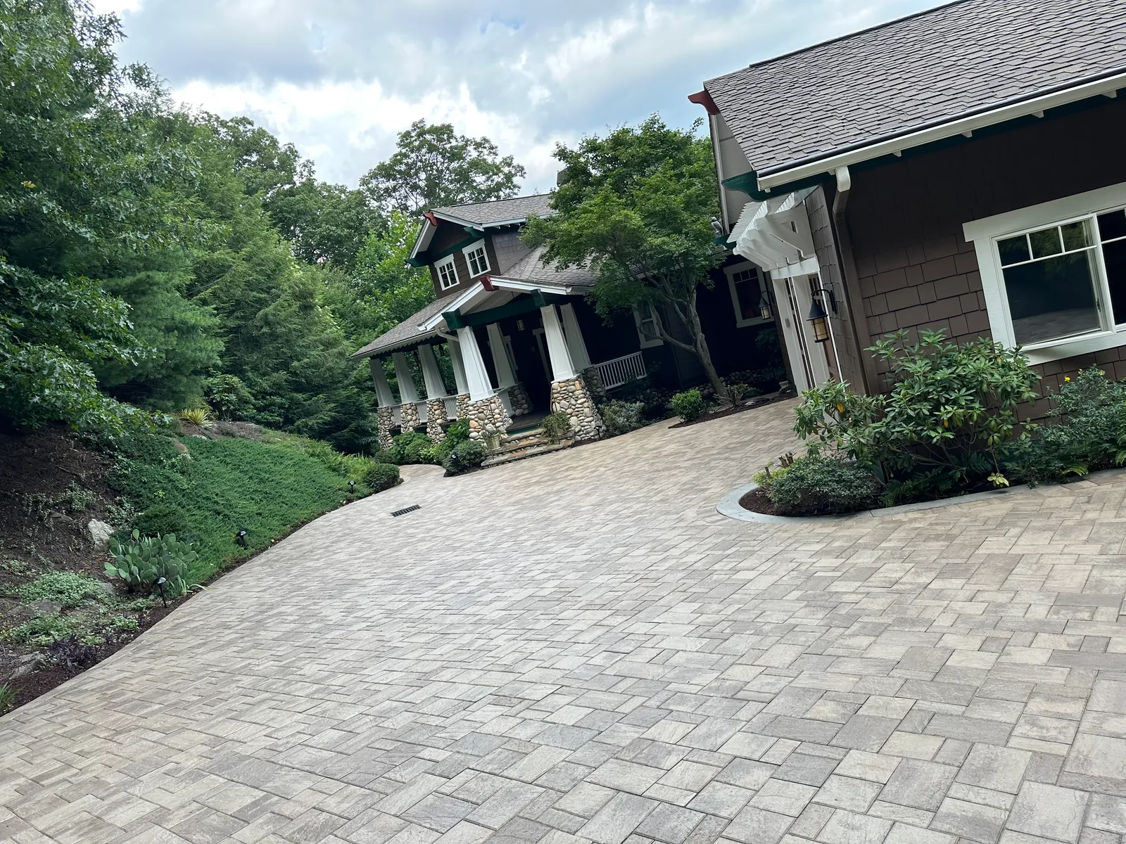Wide view of a paver driveway and motor court in front of a craftsman-style home