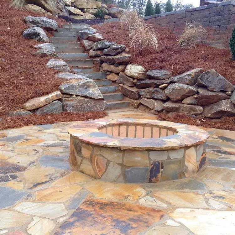 Stacked natural boulder retaining walls and stone steps leading to a hillside fire pit, low resolution
